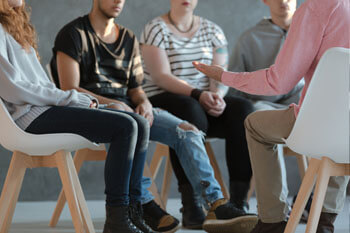 Sozialarbeiter spricht mit Jugendlichen in einem Stuhlkreis